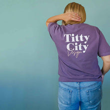 Load image into Gallery viewer, Model wearing the Body Positivity T-Shirt in plum purple, showing the back view, styled casually with jeans