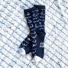 Load image into Gallery viewer, Black socks with white patterns on a textured white surface