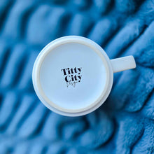 Load image into Gallery viewer, White mug with 'Titty City Design' text on a blue textured background