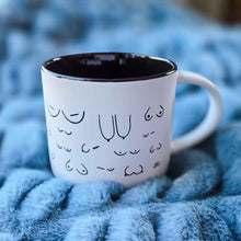 Load image into Gallery viewer, White mug with black interior and decorative text on a blue textured surface