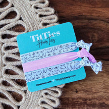 Load image into Gallery viewer, Hair tie with packaging on a textured wooden surface