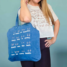 Load image into Gallery viewer, Person holding a blue tote bag with text against a teal background