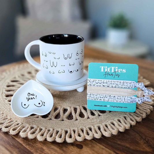 White mug with black interior, heart-shaped dish, and hair ties on a textured surface.