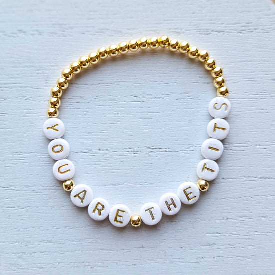 Bracelet with white beads and gold accents on a light textured background