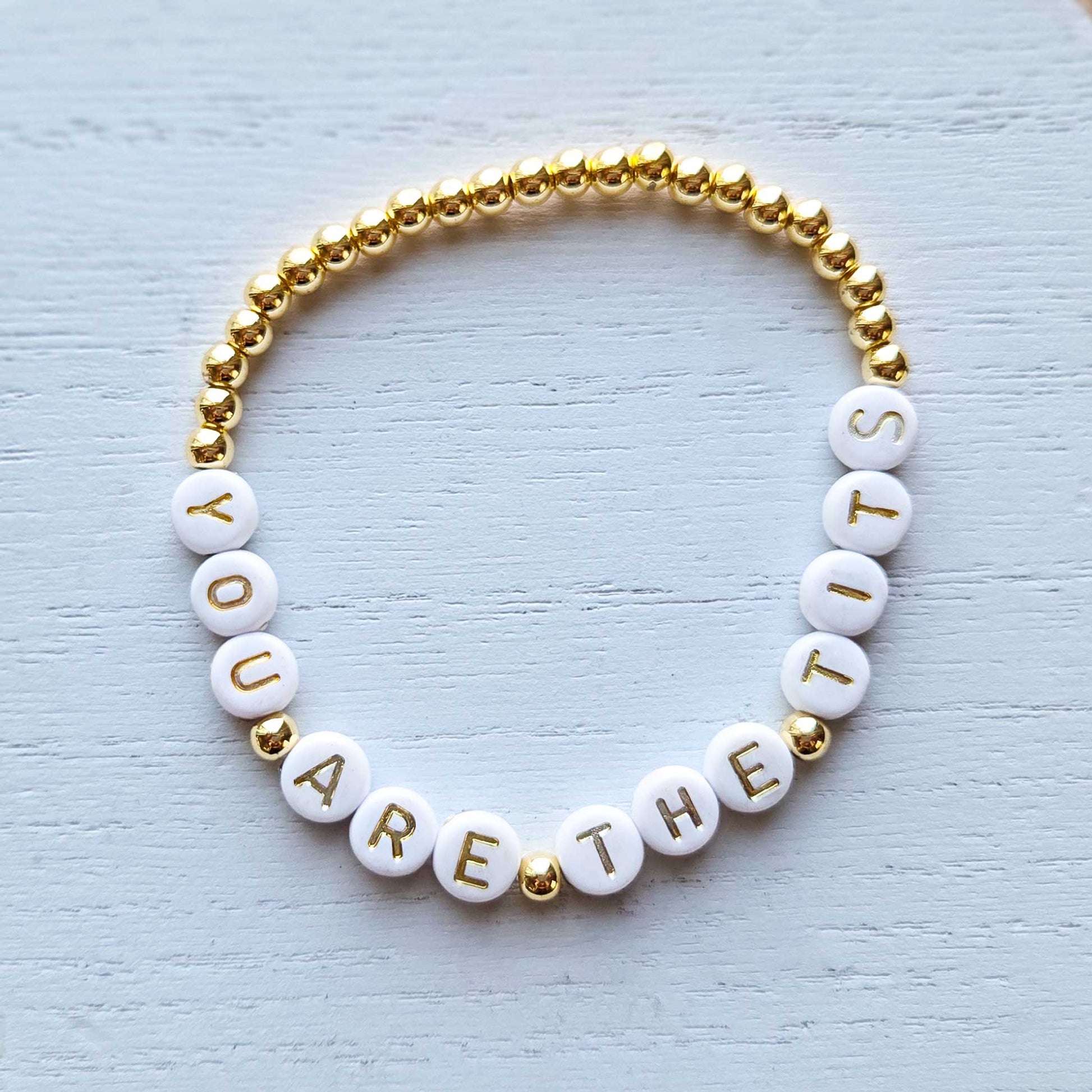 Bracelet with white beads and gold accents on a light textured background