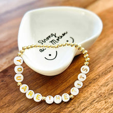 Load image into Gallery viewer, Bracelet with letter beads on a white heart shaped jewelry dish on a wooden surface
