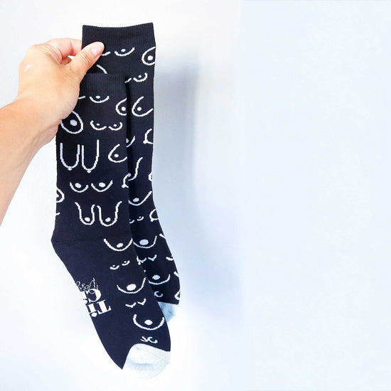 Black sock with white pattern held by a hand against a light blue background