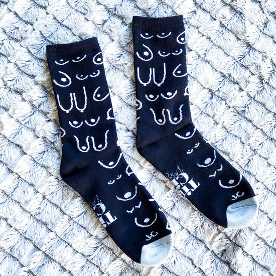 A pairs of black socks with white patterns on a textured surface