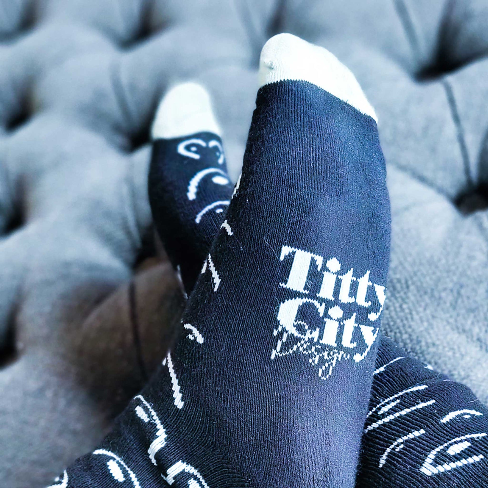 Black socks with white text and patterns on a gray ottoman