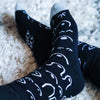 Black socks with white patterns worn on a light carpet
