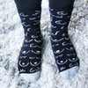 Black socks with white pattern worn on a white shag carpet