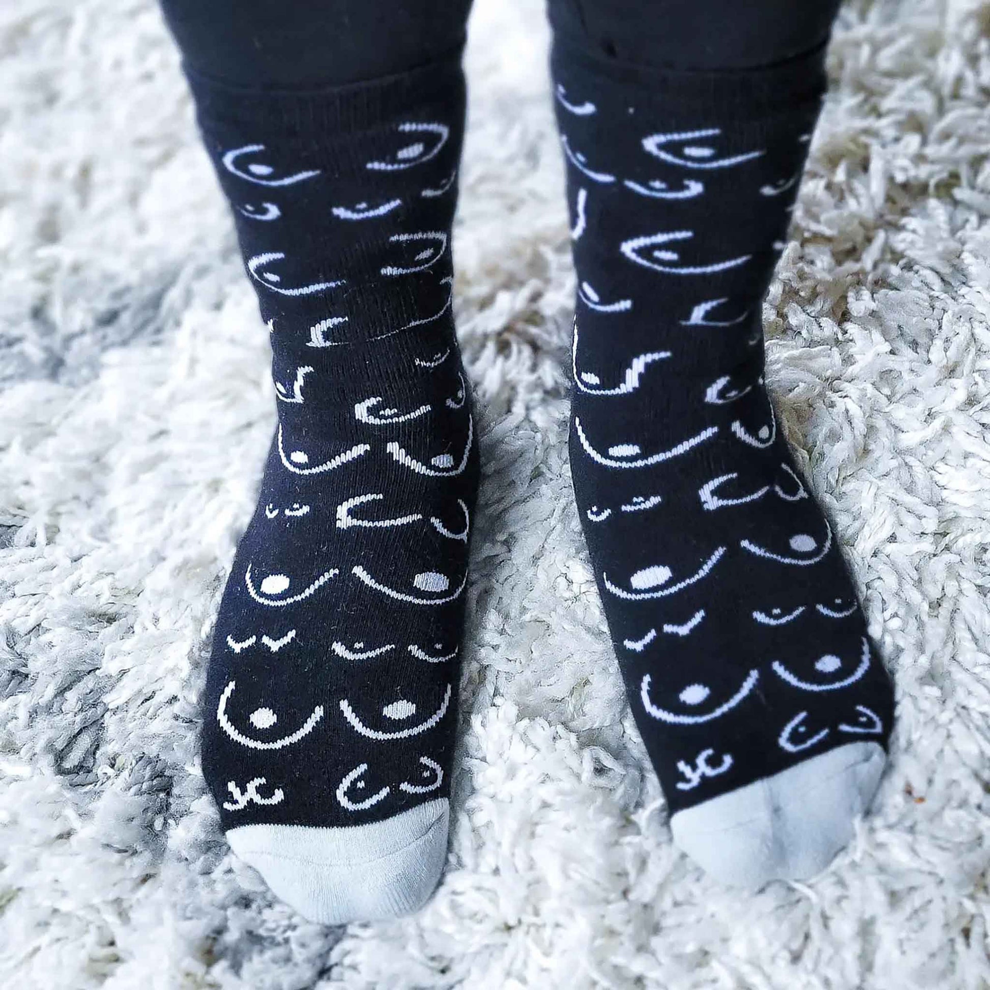 Black socks with white pattern worn on a white shag carpet