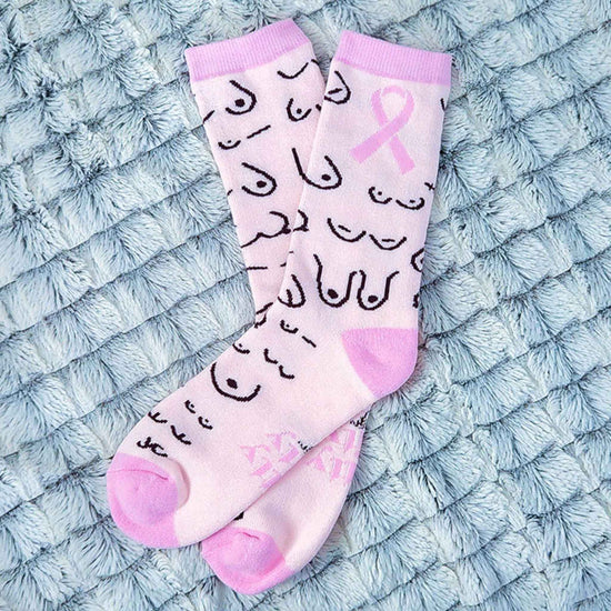 Pink socks with black patterns and a pink ribbon on a textured blue surface