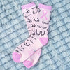 Pink socks with black patterns and a pink ribbon on a textured blue surface