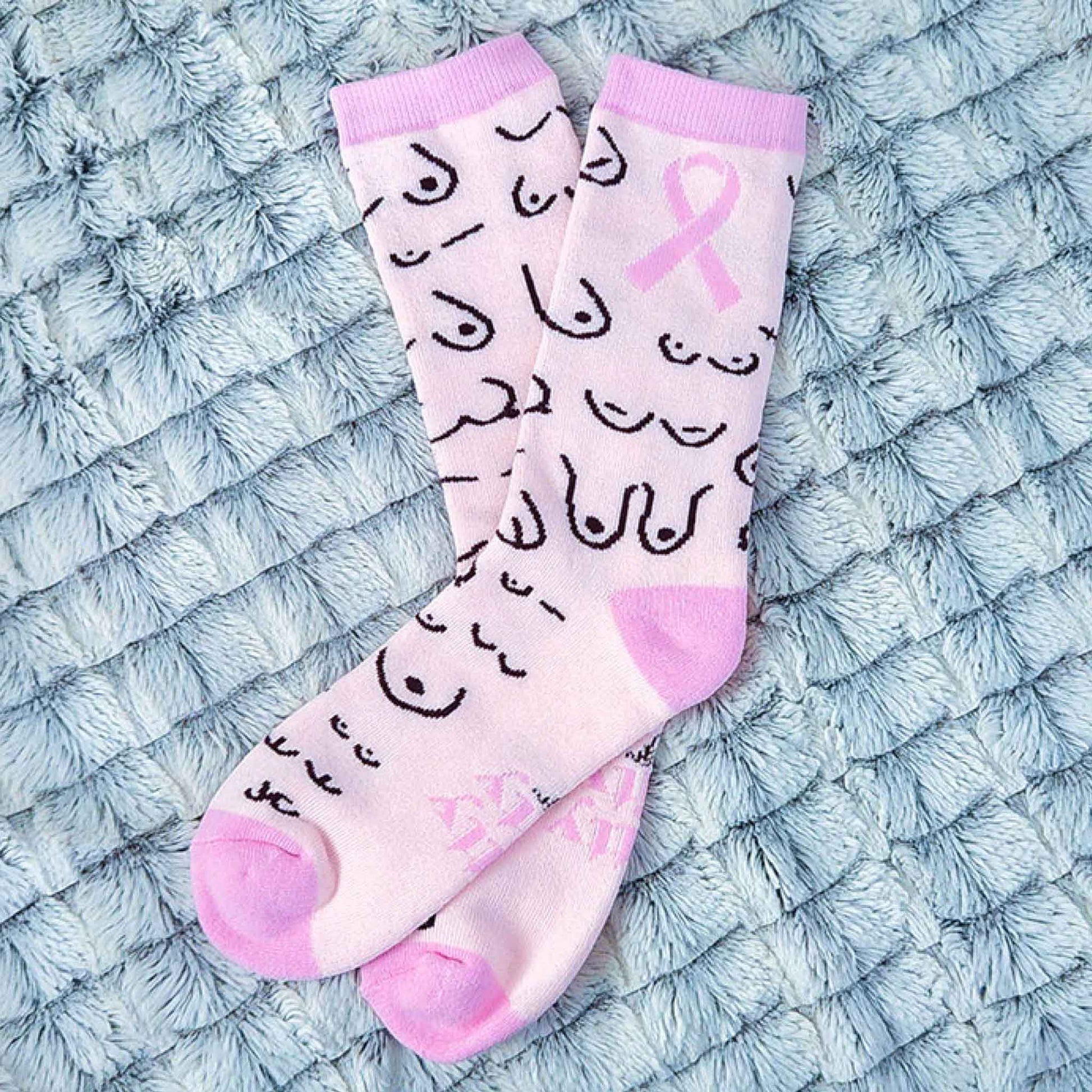 Pink socks with black patterns and a pink ribbon on a textured blue surface