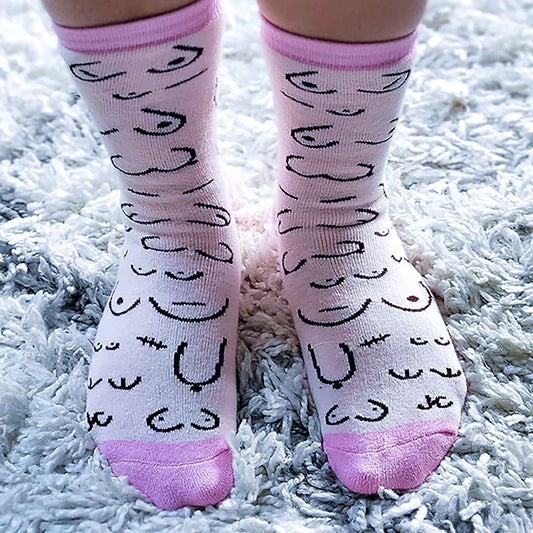 Pink socks with black abstract designs and pink toes and cuffs on a white fluffy surface