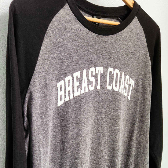 Breast Coast baseball t-shirt with gray body and black sleeves with slogan across the chest, close up, front view, on hanger