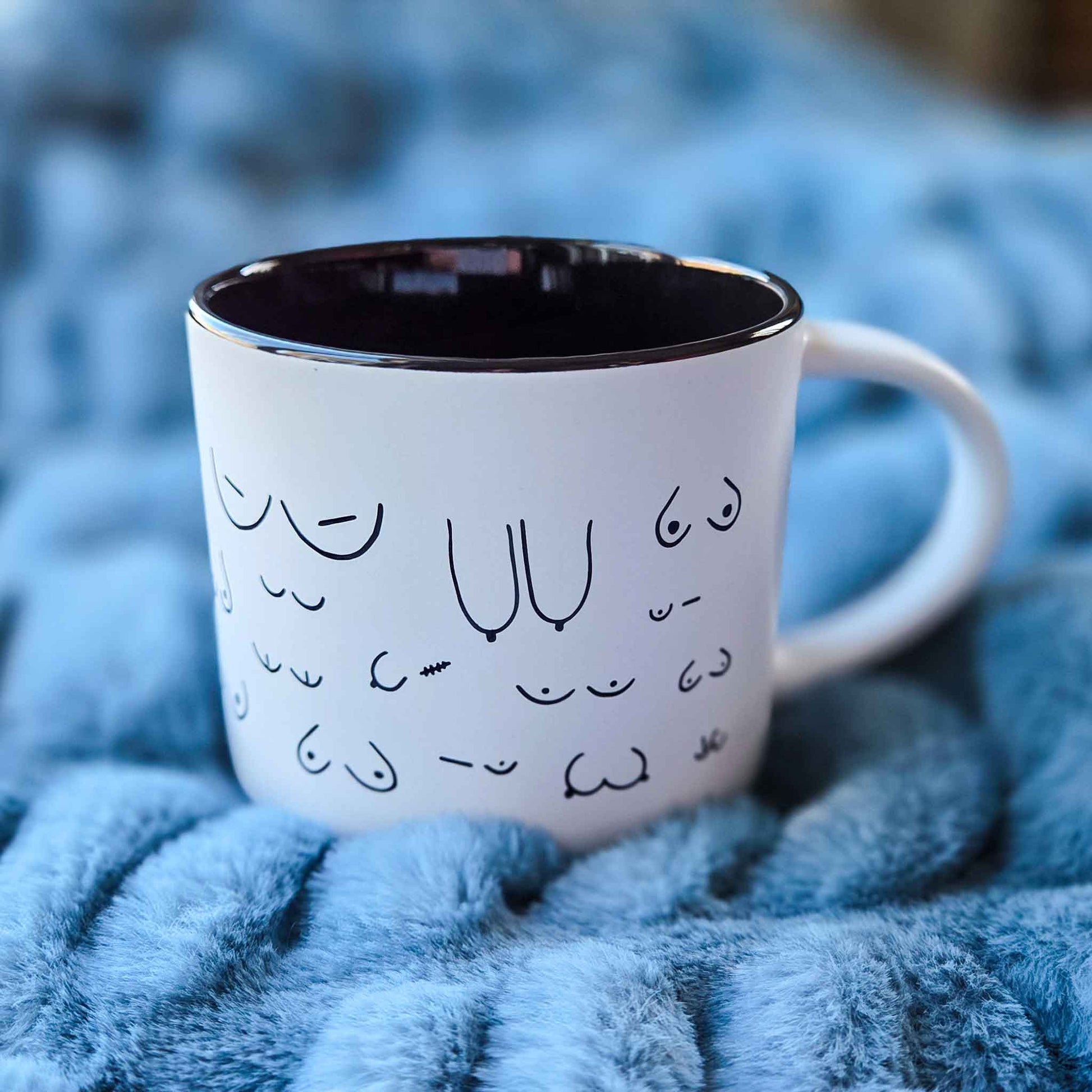 White mug with black interior and decorative text on a blue textured surface