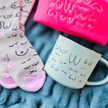 Load image into Gallery viewer, Mug and socks with cat designs on a textured surface
