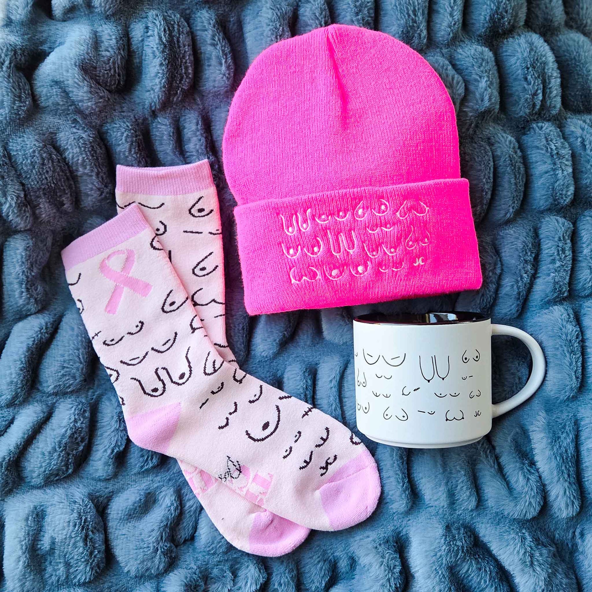 Pink beanie, socks, and mug with text on a textured blue surface