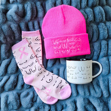 Load image into Gallery viewer, Pink beanie, socks, and mug with text on a textured blue surface
