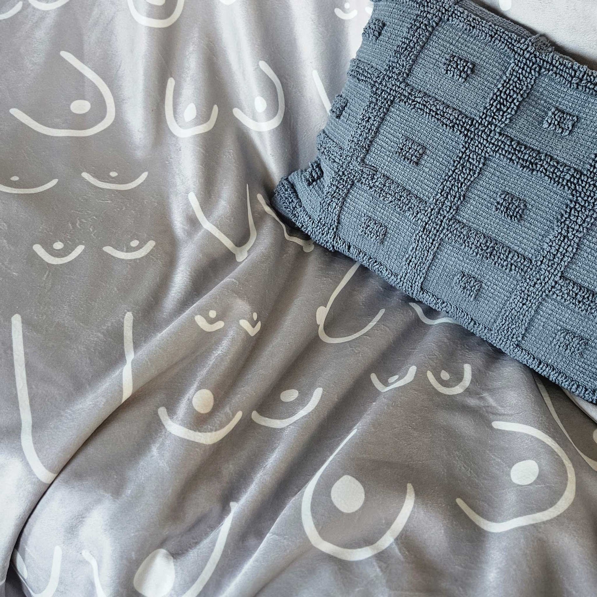 Gray blanket with white patterns and a textured blue towel on top