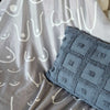 Textured blue fabric with geometric pattern on a gray background with white abstract designs