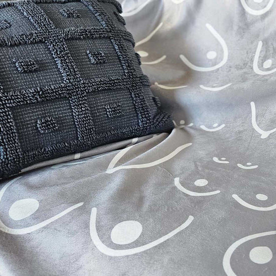 Gray textured pillow on a gray fabric surface with white patterns