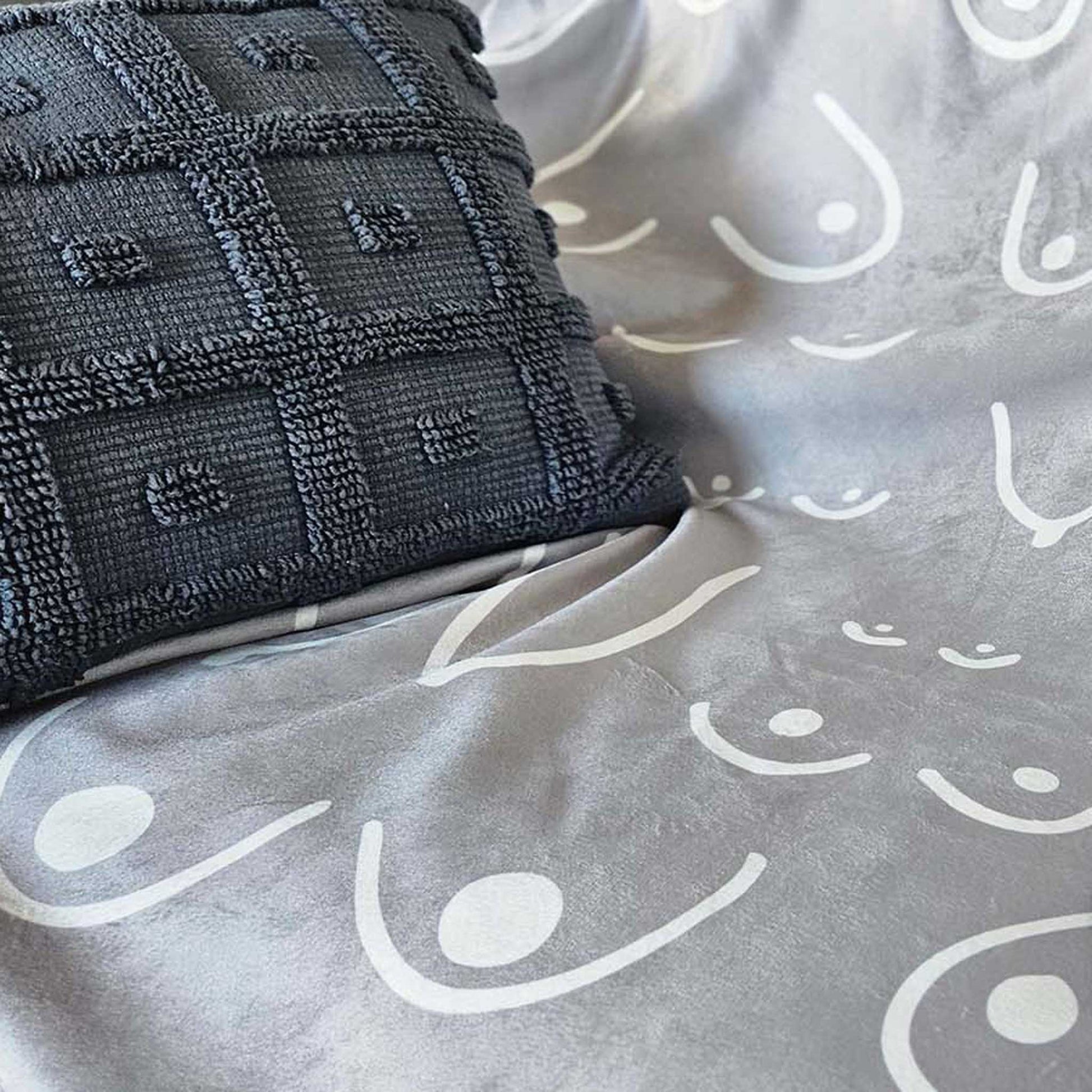 Gray textured pillow on a gray fabric surface with white patterns