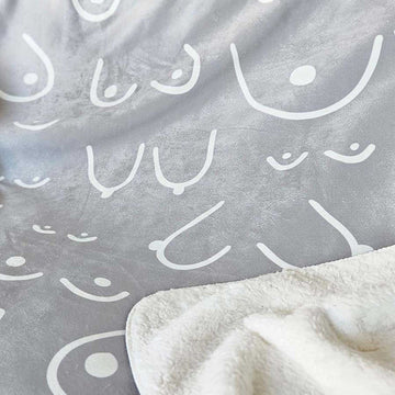 Gray blanket with white abstract patterns and a corner of a white blanket.
