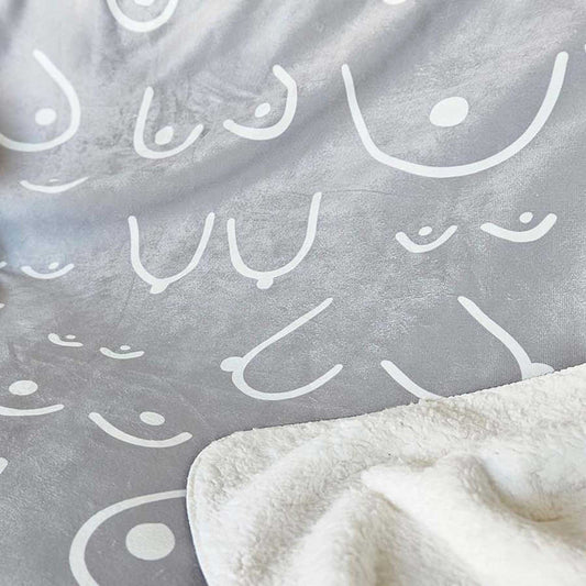 Gray blanket with white abstract patterns and a corner of a white blanket.