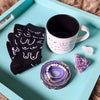 Black and white patterned socks with a white mug on a teal tray, featuring a purple decorative item.