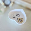 Small white dish with a gold ring inside, featuring the text 'One year!' on a light wooden surface.