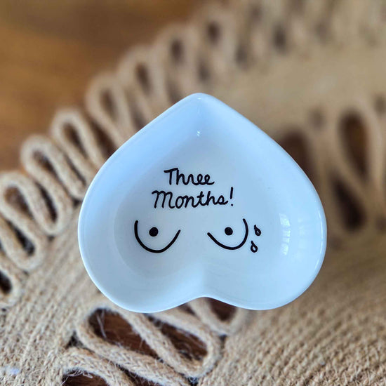 Heart-shaped white jewelry dish with 'Three Months!' text on a textured surface