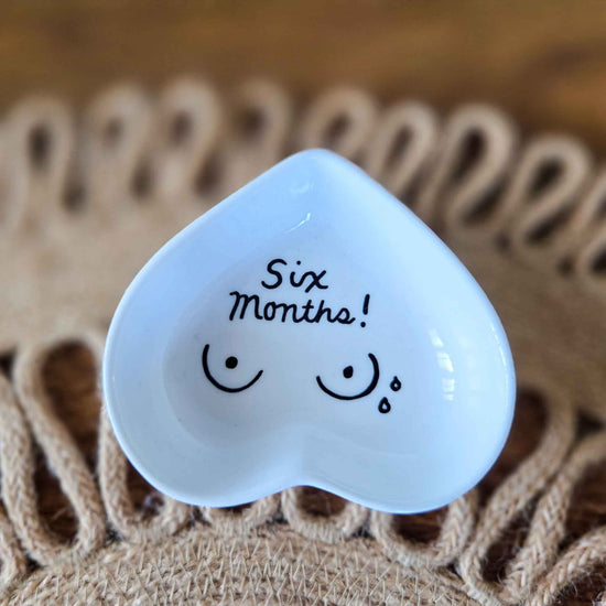 Heart-shaped jewelry dish with 'Six Months!' text on a textured surface