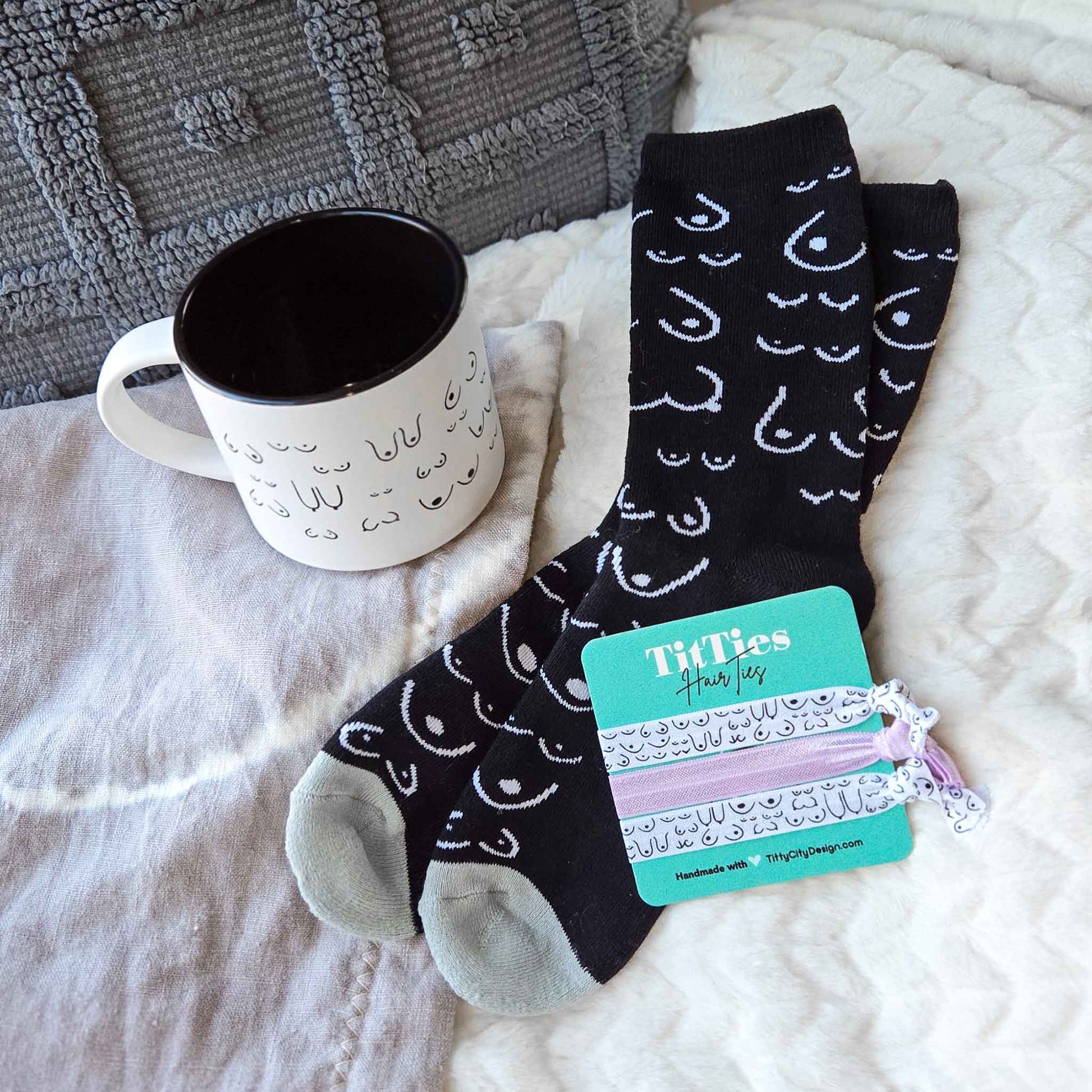 Black socks with white patterns on a white blanket next to a mug