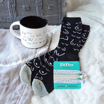 Black socks with white patterns and a mug on a bed