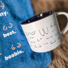 White mug with black interior and text on a blue fabric background