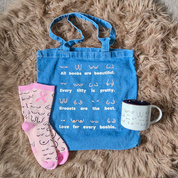 Blue tote bag with text, pink socks, and white mug on a fluffy brown surface