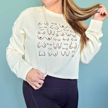 Person wearing a cream sweatshirt with a unique design on a light blue background