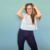 Woman wearing a white t-shirt with a design and dark pants against a light blue background
