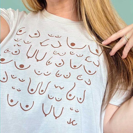 Person wearing a white tank top with design against a light blue background