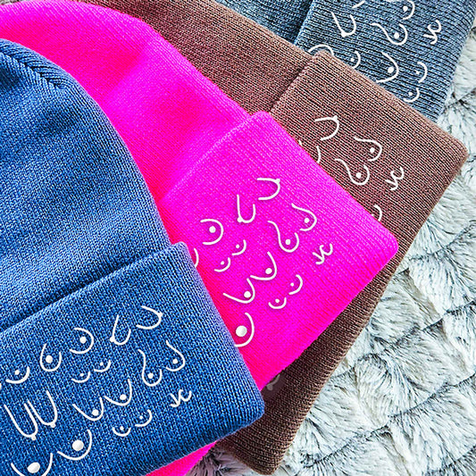Three beanies in blue, pink, and brown with white text on a textured surface.