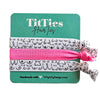 Set of 3 hair tie bracelets with bright pink hair tie in the middle on a teal card 
