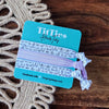 TiffTies hair ties on a branded card with decorative elements on a wooden surface