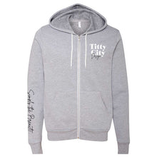 Load image into Gallery viewer, Titty City brand zip-up hooded sweatshirt in gray with logo on left chest and slogan on right sleeve, front view
