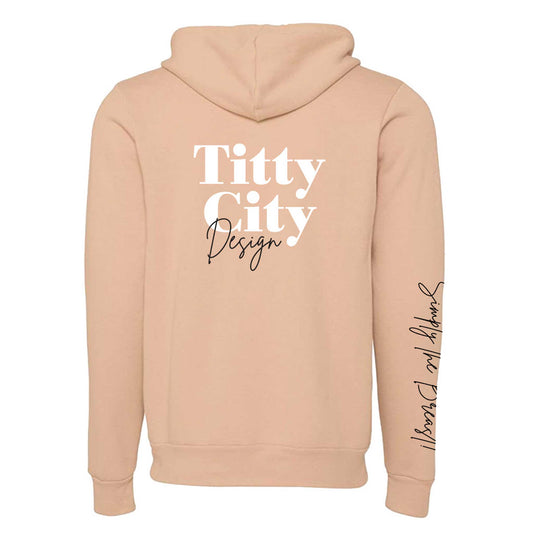 Titty City brand zip-up hooded sweatshirt in peach with logo on center back and slogan on right sleeve, back view