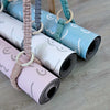 Rolls of patterned yoga mats with straps on a wooden floor